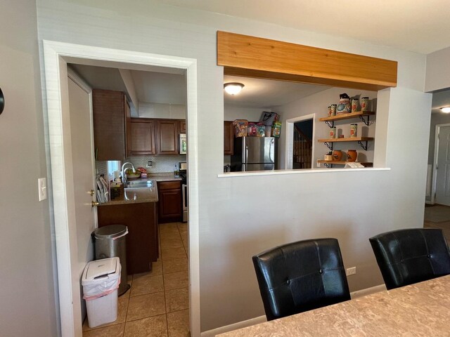 165 Kathleen Dr, Elgin, IL 60123 - kitchen featuring appliances with stainless steel finishes, a sink, light tile patterned floors, light countertops, and decorative backsplash