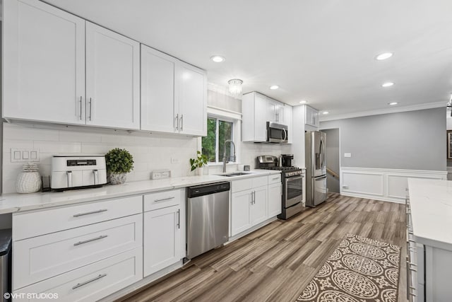 805 S Main St, Wheaton, IL 60189 - kitchen featuring appliances with stainless steel finishes, a sink, ornamental molding, white cabinets, and decorative backsplash