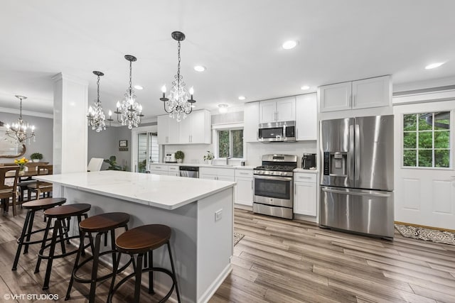 805 S Main St, Wheaton, IL 60189 - kitchen featuring stainless steel appliances, a chandelier, wood finished floors, ornamental molding, and a kitchen bar