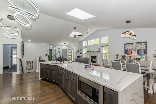 6016 W Kennedy Ct, Monee, IL 60449 - kitchen with stainless steel microwave, a sink, a stone fireplace, dark brown cabinetry, and dark wood-style flooring