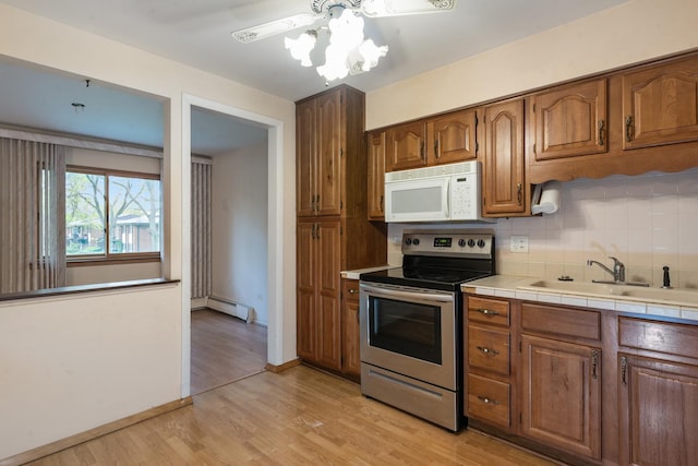 1210 N Dale Ave Unit 2I, Arlington Heights, IL 60004 - kitchen with white microwave, stainless steel electric range, a sink, a baseboard heating unit, and backsplash