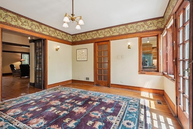 2400 Park Pl, Evanston, IL 60201 - spare room with wood finished floors, a chandelier, baseboards, crown molding, and french doors