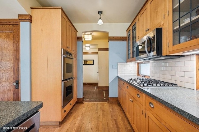 2400 Park Pl, Evanston, IL 60201 - kitchen with stainless steel appliances, decorative backsplash, dark countertops, and glass insert cabinets