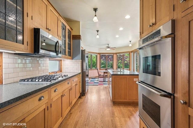 2400 Park Pl, Evanston, IL 60201 - kitchen featuring stainless steel appliances, dark countertops, light wood-type flooring, a ceiling fan, and decorative backsplash