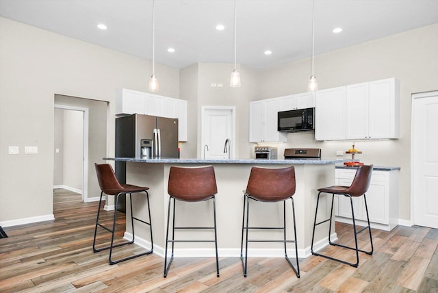 2215 N Woodlawn Park Ave, Mchenry, IL 60051 - kitchen featuring black microwave, a breakfast bar, white cabinetry, light wood-type flooring, and stainless steel fridge