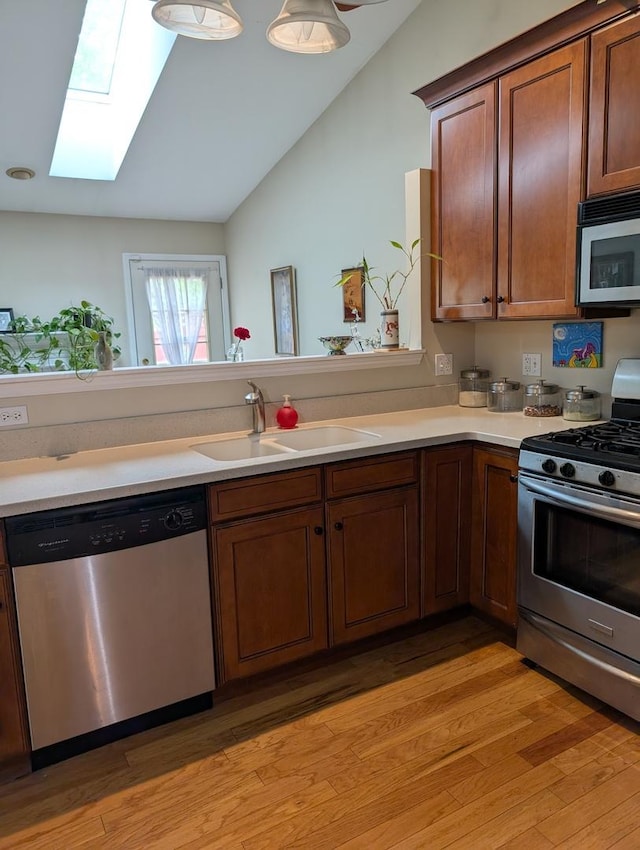 1209 Kensington Unit 1209, Mundelein, IL 60060 - kitchen with stainless steel appliances, a sink, a skylight, lofted ceiling, and light wood-style flooring