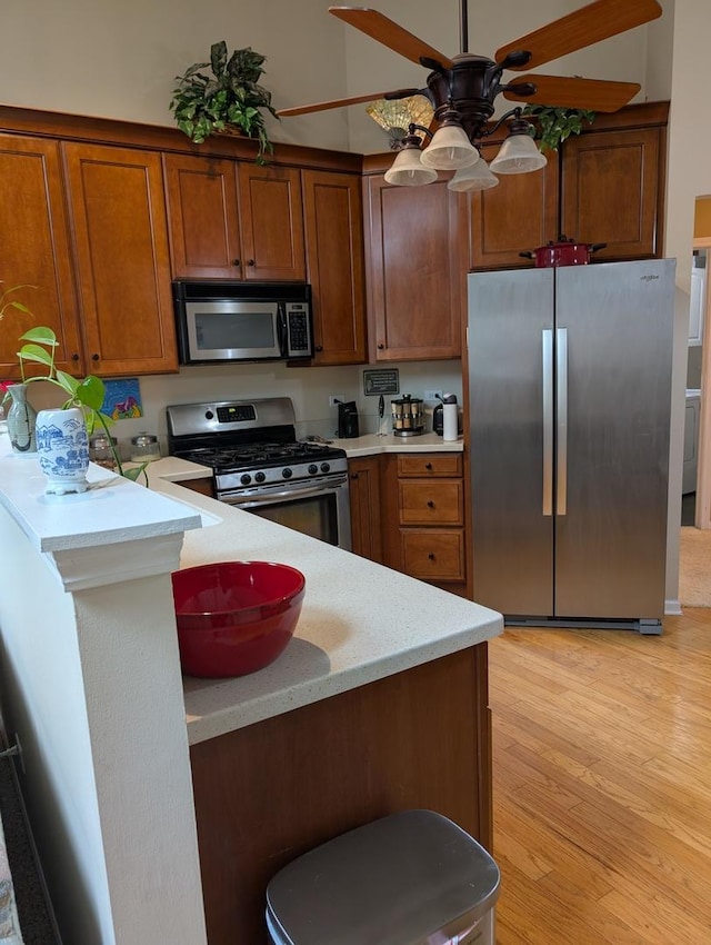 1209 Kensington Unit 1209, Mundelein, IL 60060 - kitchen with stainless steel appliances, light countertops, a ceiling fan, and brown cabinetry