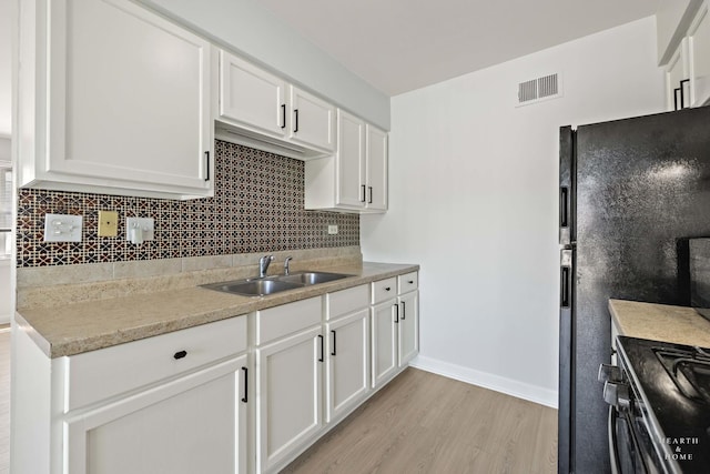 1206 Spur Ct Unit 1206, Wheeling, IL 60090 - kitchen featuring a sink, light wood-style flooring, tasteful backsplash, and white cabinetry