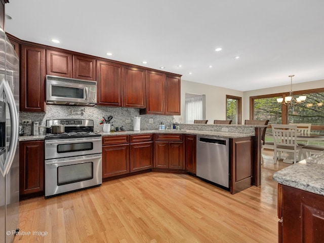 1000 Surrey Ln, Itasca, IL 60143 - kitchen with appliances with stainless steel finishes, a chandelier, light wood-style floors, tasteful backsplash, and a sink