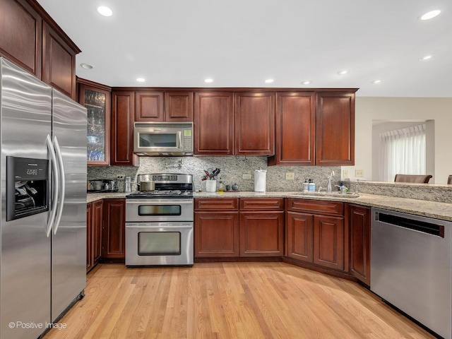 1000 Surrey Ln, Itasca, IL 60143 - kitchen with stainless steel appliances, a sink, light wood finished floors, tasteful backsplash, and light stone counters