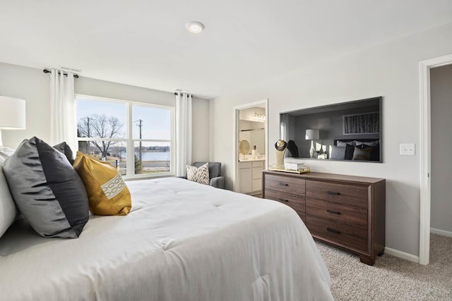 bedroom with light colored carpet, baseboards, and ensuite bath