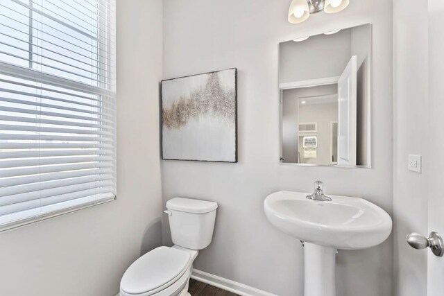 bathroom featuring toilet, baseboards, and wood finished floors