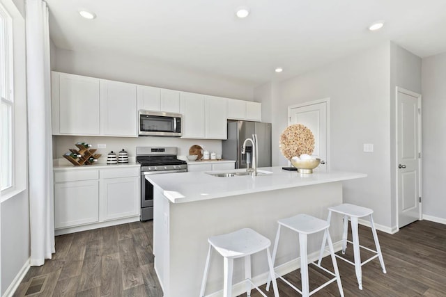 kitchen with appliances with stainless steel finishes, a sink, dark wood-type flooring, white cabinets, and recessed lighting