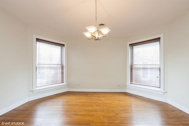 6224 N Washtenaw Ave Unit 2, Chicago, IL 60659 - empty room featuring a chandelier, wood finished floors, and baseboards