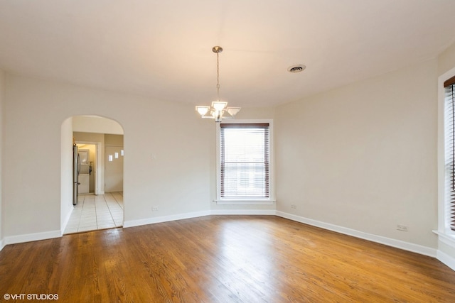 6224 N Washtenaw Ave Unit 2, Chicago, IL 60659 - spare room with a chandelier, arched walkways, wood finished floors, and baseboards