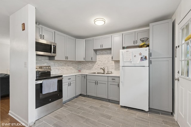 2110 Hermon Ave, Zion, IL 60099 - kitchen featuring stainless steel appliances, gray cabinetry, a sink, backsplash, and light countertops
