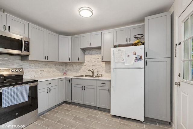 2110 Hermon Ave, Zion, IL 60099 - kitchen featuring appliances with stainless steel finishes, a sink, gray cabinets, light countertops, and decorative backsplash