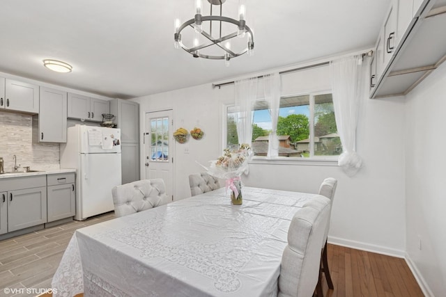 2110 Hermon Ave, Zion, IL 60099 - dining room featuring a chandelier, light wood-style flooring, and baseboards