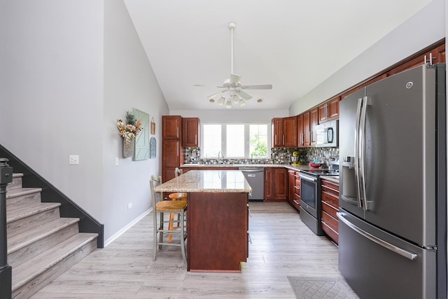413 W Cook St, Manteno, IL 60950 - kitchen with appliances with stainless steel finishes, ceiling fan, a kitchen island, a kitchen bar, and decorative backsplash