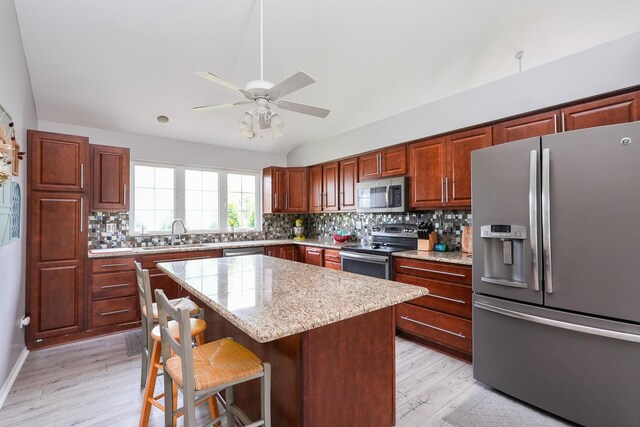 413 W Cook St, Manteno, IL 60950 - kitchen featuring appliances with stainless steel finishes, light wood-style floors, a sink, a breakfast bar, and a kitchen island