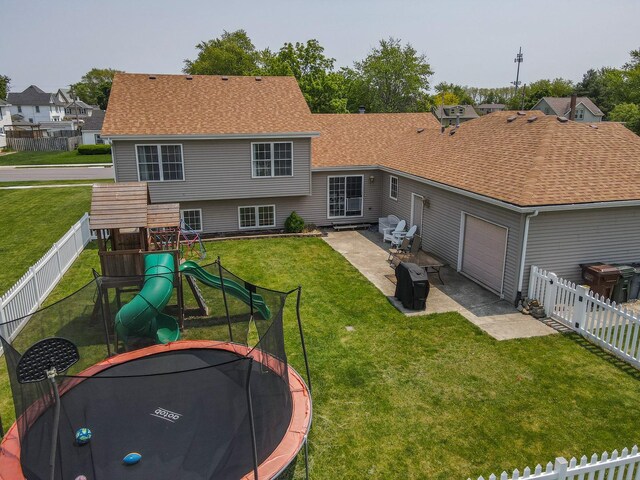 413 W Cook St, Manteno, IL 60950 - rear view of property featuring a trampoline, a playground, a patio area, an attached garage, and a shingled roof