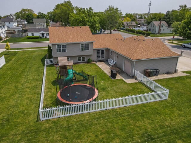 413 W Cook St, Manteno, IL 60950 - back of house featuring a trampoline, an attached garage, a residential view, a playground, and roof with shingles