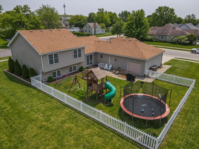 413 W Cook St, Manteno, IL 60950 - rear view of house featuring a trampoline, a playground, a garage, roof with shingles, and a patio