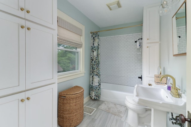 2013 E Taylor St, Bloomington, IL 61701 - full bathroom featuring shower / bathtub combination with curtain, toilet, and wood finished floors