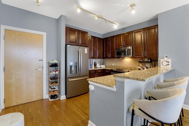 1629 S Prairie Ave Unit 1503, Chicago, IL 60616 - kitchen with appliances with stainless steel finishes, a peninsula, a breakfast bar area, light wood-style floors, and backsplash