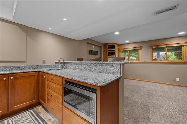 10N738 Prairie Xing, Elgin, IL 60124 - kitchen featuring stainless steel microwave, a sink, light stone countertops, baseboards, and brown cabinetry