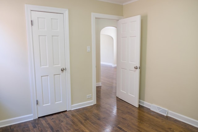 2702 N 76th Ave, Elmwood Park, IL 60707 - unfurnished bedroom featuring arched walkways, crown molding, dark wood-type flooring, and baseboards