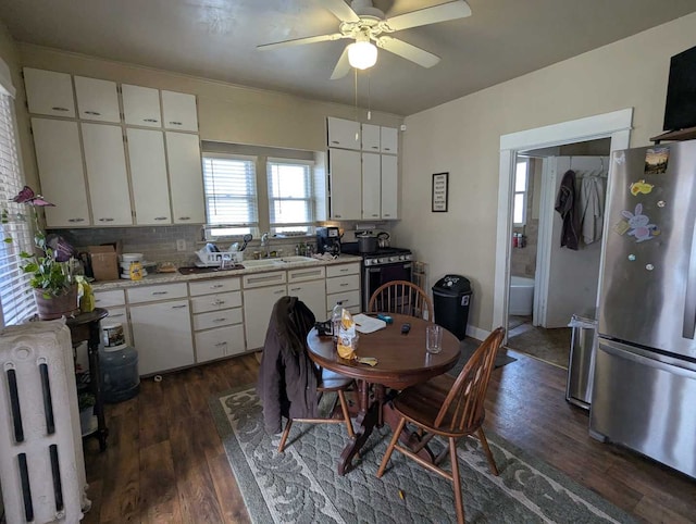 1215 3rd St, Moline, IL 61265 - kitchen featuring appliances with stainless steel finishes, light countertops, white cabinetry, dark wood-style flooring, and radiator heating unit