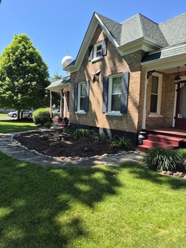 123 W Maple St, Franklin Grove, IL 61031 - view of side of home featuring a lawn, brick siding, and a porch