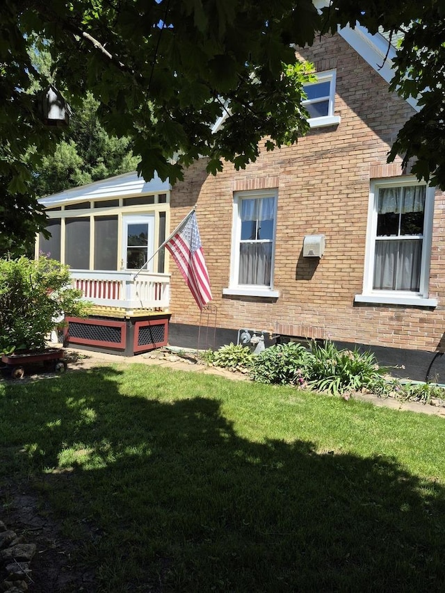 123 W Maple St, Franklin Grove, IL 61031 - view of property exterior with a sunroom, a yard, and brick siding