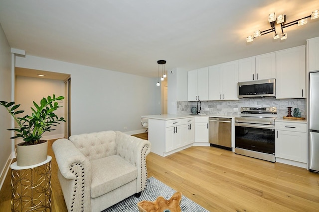 6300 N Sheridan Rd Unit 112, Chicago, IL 60660 - kitchen with stainless steel appliances, a sink, a peninsula, backsplash, and white cabinets