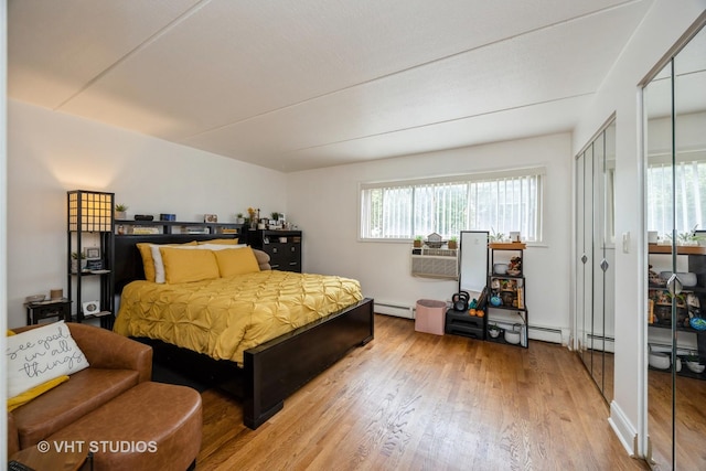 914 N Austin Blvd Unit B10, Oak Park, IL 60302 - bedroom with wood finished floors, a baseboard radiator, multiple closets, and a wall mounted air conditioner