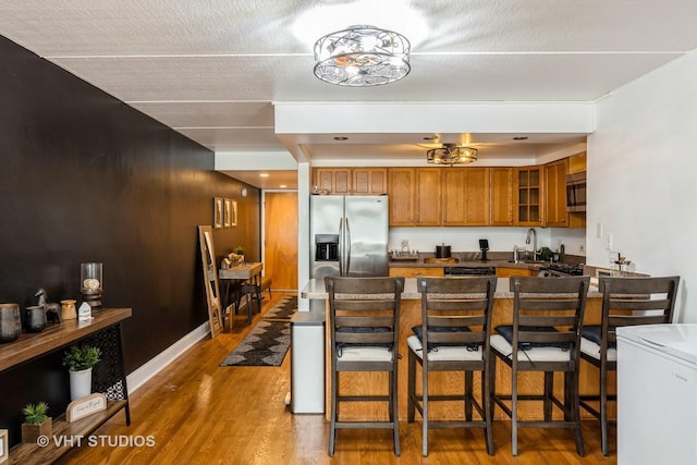 914 N Austin Blvd Unit B10, Oak Park, IL 60302 - kitchen featuring stainless steel appliances, brown cabinetry, wood finished floors, and a kitchen bar
