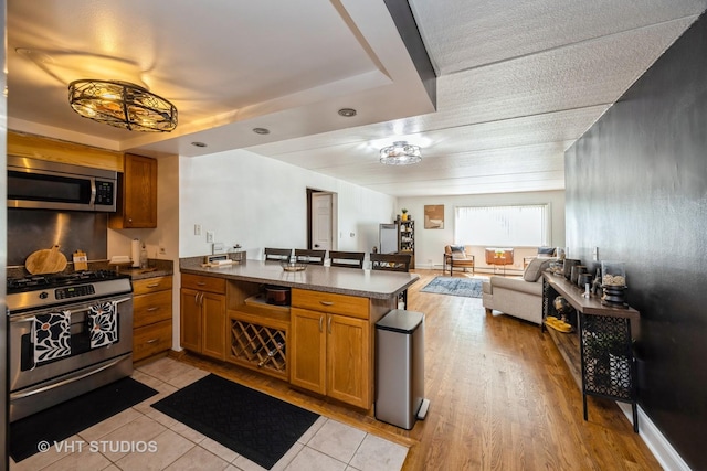 914 N Austin Blvd Unit B10, Oak Park, IL 60302 - kitchen with stainless steel appliances, open floor plan, a peninsula, and brown cabinets
