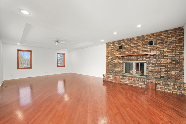 975 Patriot Ln, Hoffman Estates, IL 60192 - unfurnished living room featuring a fireplace, wood finished floors, a tray ceiling, a ceiling fan, and recessed lighting