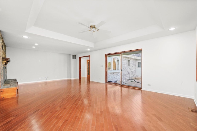 975 Patriot Ln, Hoffman Estates, IL 60192 - unfurnished living room featuring a raised ceiling, ceiling fan, a large fireplace, light wood-style floors, and baseboards