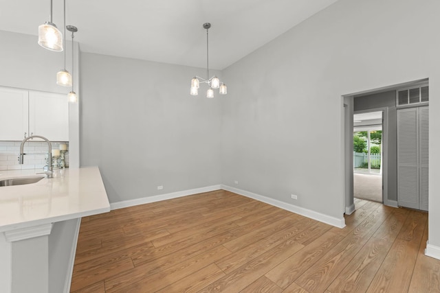 1802 77th St, Naperville, IL 60565 - unfurnished dining area with a sink, light wood-style floors, a chandelier, baseboards, and high vaulted ceiling