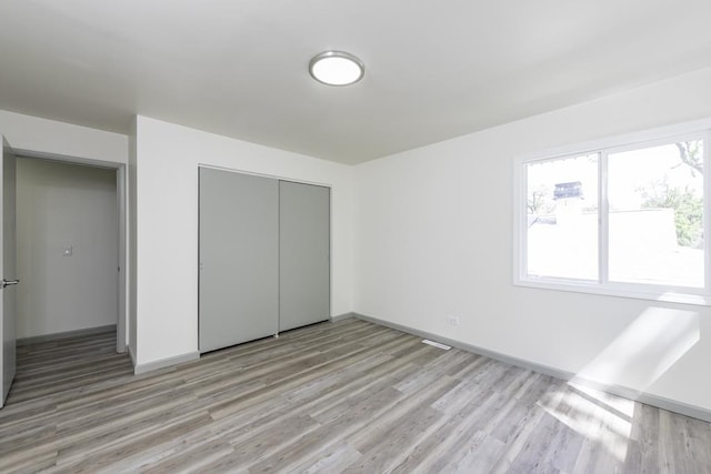 1525 Grove Dr, Round Lake Beach, IL 60073 - unfurnished bedroom featuring light wood-style flooring, a closet, and baseboards