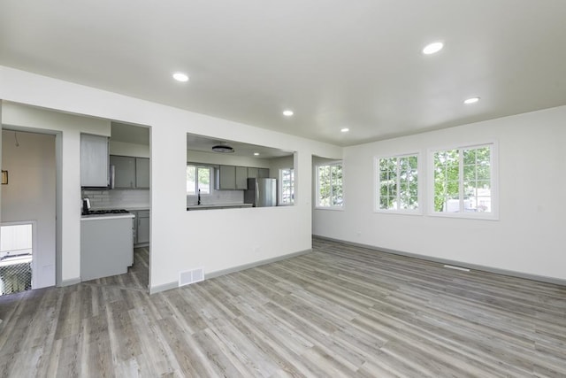 1525 Grove Dr, Round Lake Beach, IL 60073 - unfurnished living room featuring light wood-style flooring, recessed lighting, a sink, and baseboards