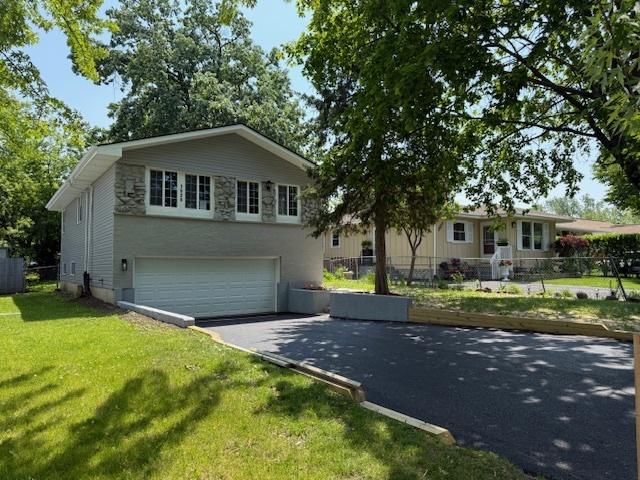 1525 Grove Dr, Round Lake Beach, IL 60073 - view of front facade featuring driveway, a garage, and stone siding