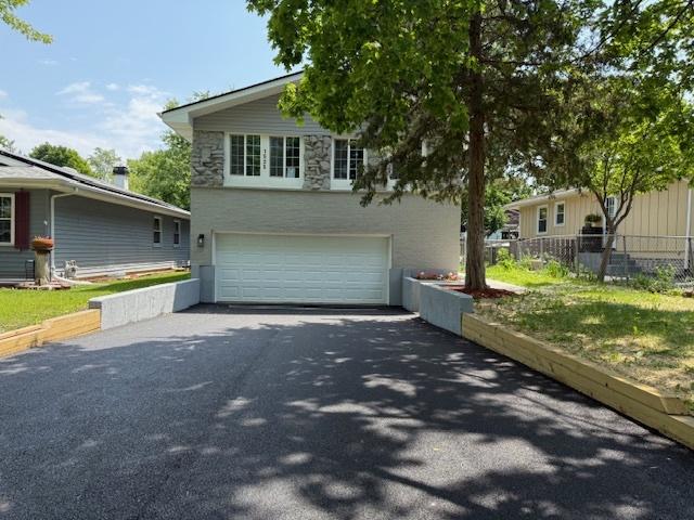 1525 Grove Dr, Round Lake Beach, IL 60073 - view of front of house with driveway, an attached garage, and stone siding