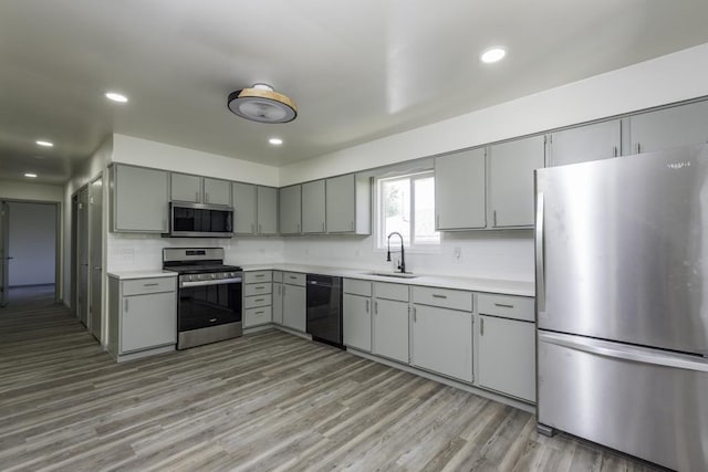 1525 Grove Dr, Round Lake Beach, IL 60073 - kitchen with stainless steel appliances, gray cabinetry, a sink, light countertops, and light wood-style floors