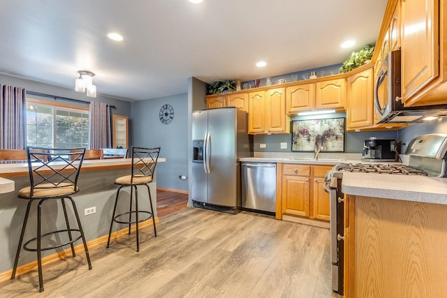 18225 Eagle Dr, Tinley Park, IL 60477 - kitchen featuring appliances with stainless steel finishes, a kitchen bar, a sink, light countertops, and light wood-style flooring