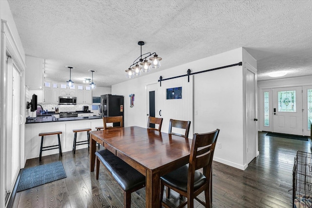 956 E Orleans St, Paxton, IL 60957 - dining space featuring a barn door, dark wood-style flooring, and a textured ceiling