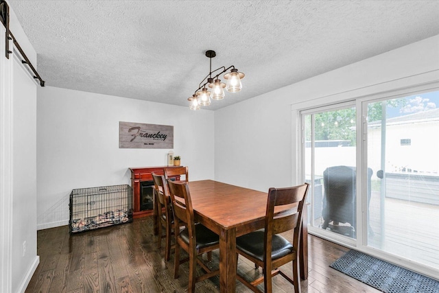 956 E Orleans St, Paxton, IL 60957 - dining room featuring dark wood-type flooring, a textured ceiling, baseboards, and a barn door