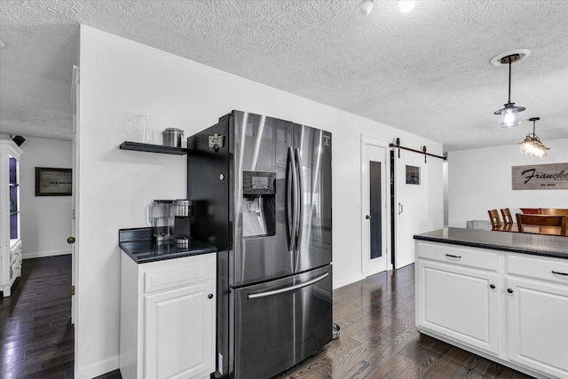 956 E Orleans St, Paxton, IL 60957 - kitchen featuring stainless steel fridge with ice dispenser, a barn door, a textured ceiling, dark wood finished floors, and dark countertops